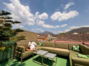 a woman sitting on a couch on a balcony at Tropicana La Catedral in Antigua Guatemala