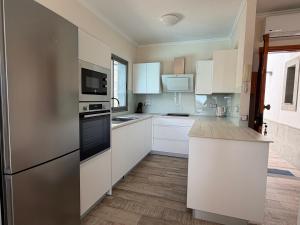 a kitchen with white cabinets and black appliances at Villa Sunset Tauro in Mogán