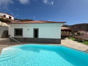 a large blue swimming pool in front of a house at Villa Sunset Tauro in Mogán