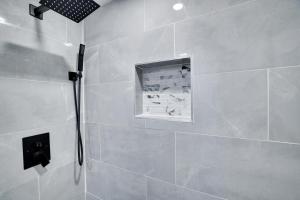a bathroom with a shower with a tile wall at 4BR Newark Stay w/ Parking And Fast Wi-Fi in Newark