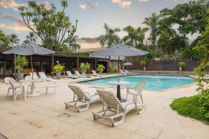 a pool with chairs and tables and umbrellas at Delphin Beach Hotel - Suíte 238 in Guarujá