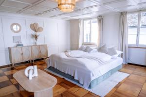 a white bedroom with a large bed and a table at Cara Nima Schwyz in Schwyz
