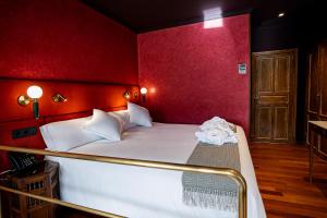 a bedroom with a large bed with red walls at Casa Inquieta Hotel Boutique in Seville +26 photos