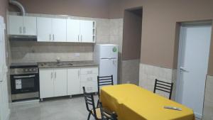 a kitchen with white cabinets and a yellow table and chairs at Departamentos 12 de Mayo in Salsipuedes