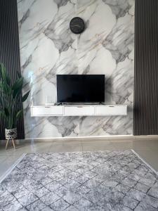 a living room with a tv on a marble wall at Cloud9 Homestay D Aman Residence in Alor Setar