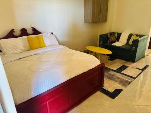 a bedroom with a bed and a chair and a couch at Bella apartment studios town in Meru