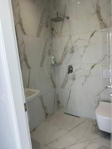 a white bathroom with a toilet and a sink at Qyteza guest house in Shkodër