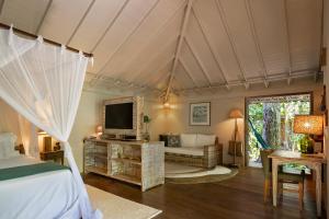 a bedroom with a bed and a tv in a room at Pousada Capim Santo in Trancoso