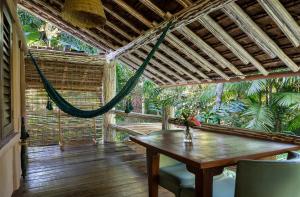 a porch with a hammock and a table and chairs at Pousada Capim Santo in Trancoso