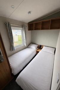 two beds in a small room with a window at Luxury 3 bed sleeps 8 caravan with sea view in Exmouth