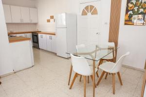 a kitchen with a glass table and white chairs at Spacious 2 BR appartment near mall -Internet 1Gbps in Paphos