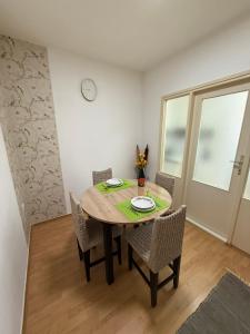 a dining room table with chairs and a clock on the wall at Apartman Ditta in Subotica +2 photos