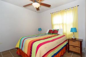 a bedroom with a colorful bed and a ceiling fan at Beautiful Huge Beachfront Home Serenity Beach in Puerto Peñasco