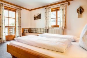 two beds in a bedroom with two windows at Reitbauernhof in Grossarl