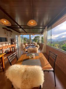 a dining room with a table and chairs and windows at Mirante das Montanhas in Pedra Menina