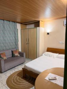 a hotel room with two beds and a couch at Studio spacieux Aéroport FHB in Abidjan