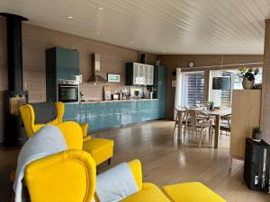 a living room with yellow furniture and a kitchen at Modern cabin with panoramic views in Porsgrunn +18 photos