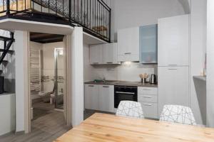 a kitchen with white cabinets and a dining table at Monolocale Piazza Garibaldi in Saluzzo