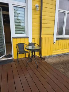 a table and two chairs on a deck next to a yellow house at A&A Apartment Vilnius 2 in Vilnius