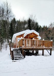 a wooden cabin with a snow covered roof in the snow at Le Chaleureux, Picanoc River in Kazabazua +10 photos