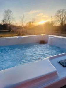 a hot tub with the sunset in the background at Domek z jacuzzi Studnica 39 in Studnica