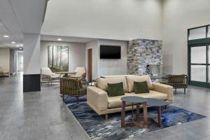 a lobby with a couch and tables and a fireplace at Fairfield by Marriott Inn & Suites LaGrange in La Grange
