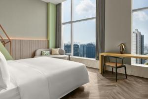 a hotel room with a bed and a desk and window at AC Hotel by Marriott Hangzhou in Hangzhou