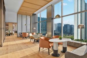 an office lobby with tables and chairs and large windows at AC Hotel by Marriott Hangzhou in Hangzhou
