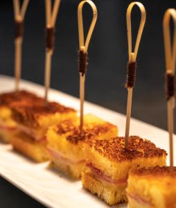 a group ofasted sandwiches on a plate with wooden sticks at Le Celtique & Spa in Carnac