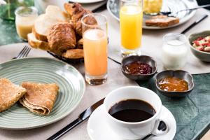 a table topped with plates of food and a cup of coffee at Le Celtique & Spa in Carnac