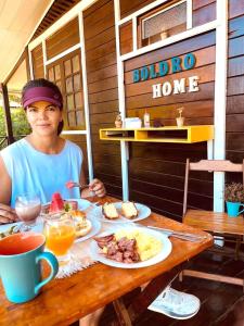 a woman sitting at a table with a plate of food at Pousada Boldró Home in Fernando de Noronha
