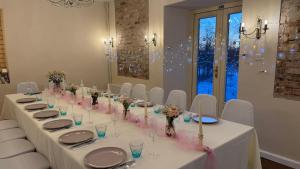 a long table with white chairs and pink flowers at Gaiziņstars in Bērzaune