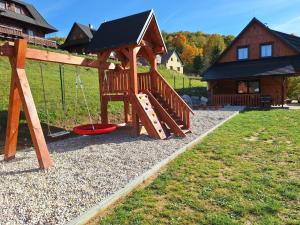 a wooden playground with a slide in a yard at Chata do Zlatneho in Terchová