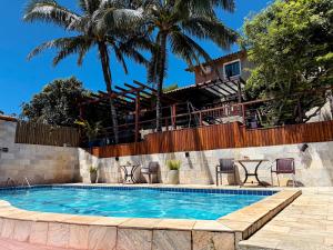 a swimming pool in front of a house with palm trees at Calador Búzios Hotel in Búzios