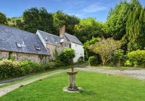an old stone house with a bird bath in the yard at Worthy Cottage Porlock Weir in Porlock