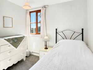 a bedroom with a bed and a dresser and a window at Barn Cottage Brayford in Charles