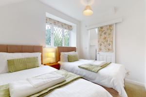 two beds in a room with white walls and windows at Plum Tree Cottage Porlock in Porlock