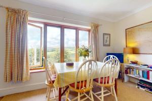 a dining room with a table and chairs and windows at Hillway Lodge Withypool in Withypool