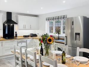 a kitchen with a table and chairs and a kitchen with white cabinets at Meadow View Brushford in Dulverton