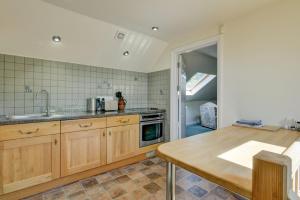 a kitchen with wooden cabinets and a sink and a table at Dunkery View Wootton Courtenay in Minehead
