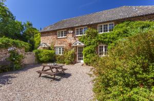 a stone house with a picnic table in front of it at Luccombe Cottage Luccombe in Luccombe