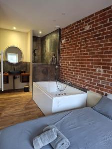 a bedroom with a large bath tub next to a brick wall at Spa d'Assier in Feurs