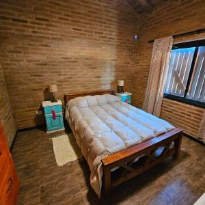 a large bed in a room with a brick wall at Cabaña Mica in Nono