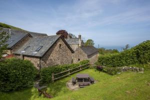 an old stone house with a picnic table in the yard at Yenworthy Mill Countisbury in Countisbury