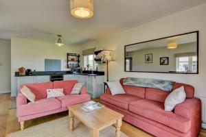 a living room with two red couches and a table at Linhay Cottage Withypool in Withypool +11 photos