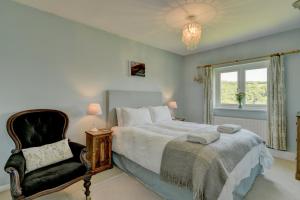 a bedroom with a bed and a chair and a window at Linhay Cottage Withypool in Withypool