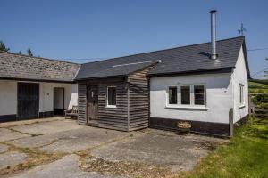a small white house with a driveway at Linhay Cottage Withypool in Withypool