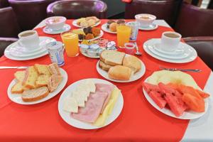 a red table with plates of food on it at Hotel Golden Park Campinas Cambuí By Nacional Inn in Campinas
