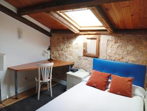 a bedroom with a bed with a blue headboard and a desk at El rincón de Atenea Tu casa cerca de Guadalajara in Aldeanueva de Guadalajara