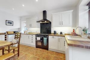 a kitchen with white cabinets and a stove top oven at Bowness Porlock in Porlock +26 photos